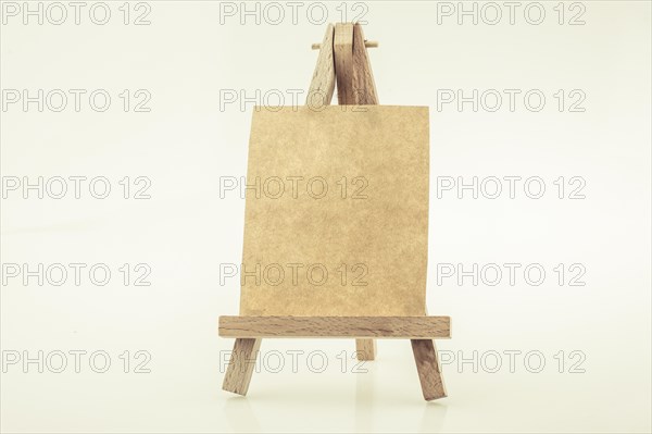 Brown color notepaper on a painting tripod on white background