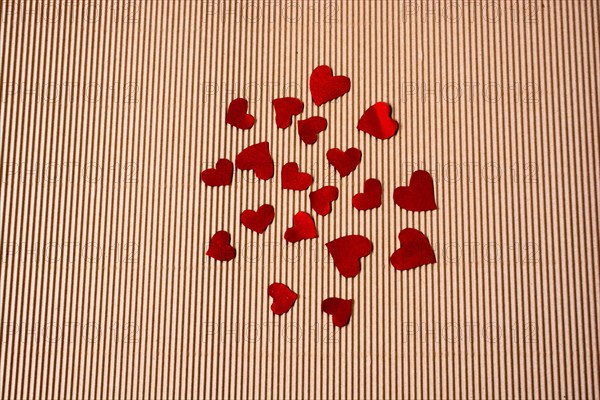 Red color paper hearts on a brown color cardboard