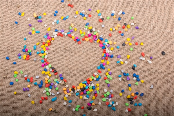 Colorful little pebbles form a heart shape on canvas ground