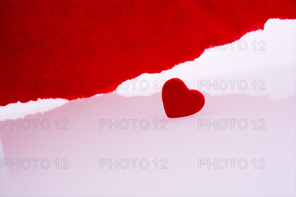 Heart near torn red paper on a white background