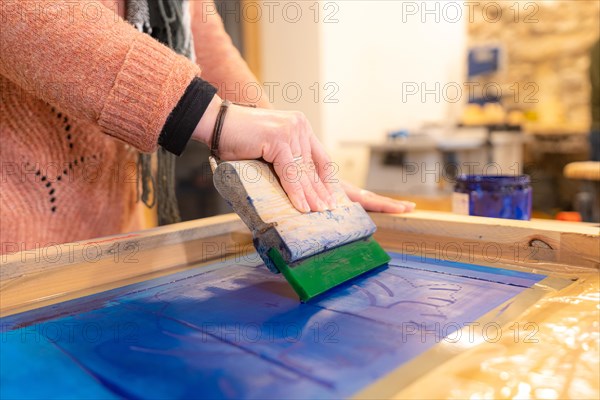 Close-up of an artist and printmaker working a printing press