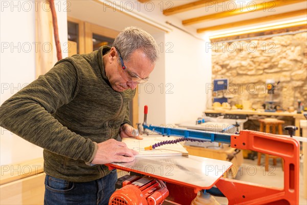 Elder expertise carpenter cutting wood in a workshop