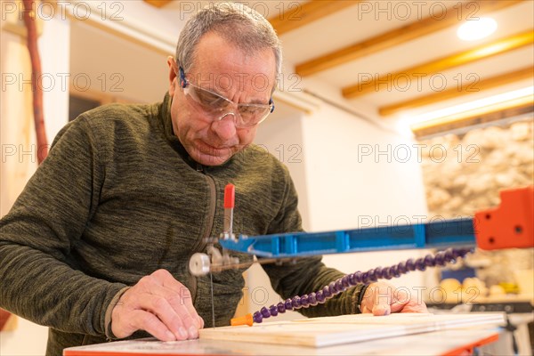 Low angle view close-up of a concentrated carpenter cutting a piece of wood in workshop
