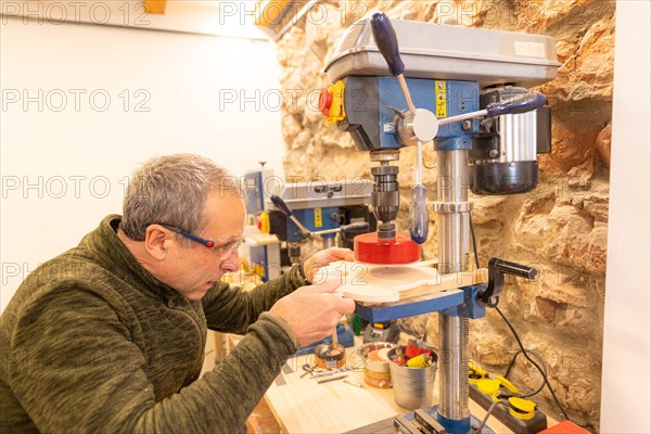 Side view of a elder expertise carpenter using a sander on a piece of wood