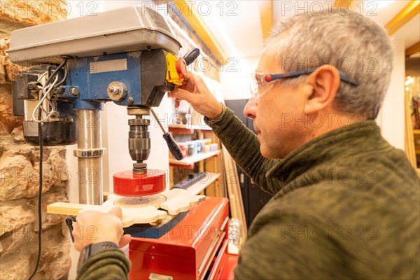 Close-up of a carpenter using a sander to make a hole in a piece of wood