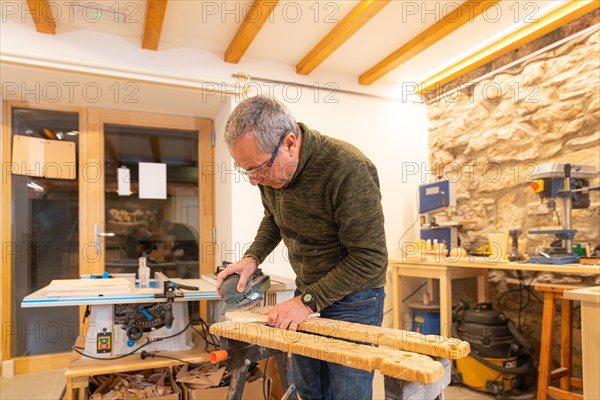 Carpenter using an electric tool to sanding a piece of wood in a workshop alone