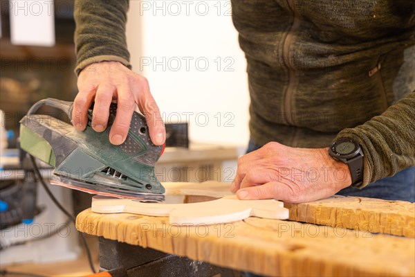 Close-up of a carpenter polishing a hole in a piece of wood using an electric tool