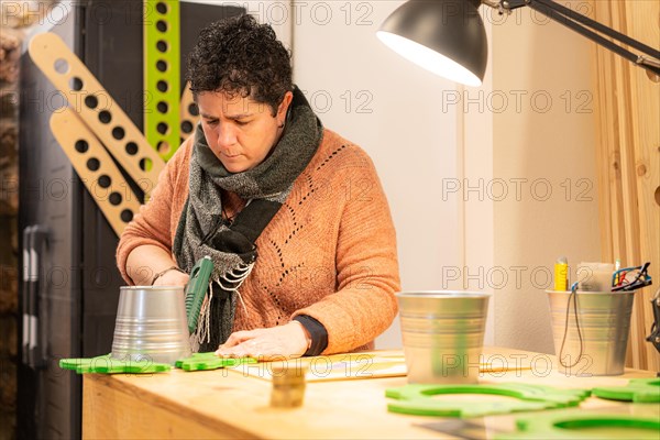 Woman using a tool to attach pieces of wood with glue in a workshop