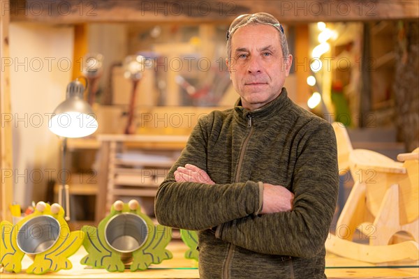 Portrait of a mature carpenter and artisan in a workshop standing proud with arms crossed