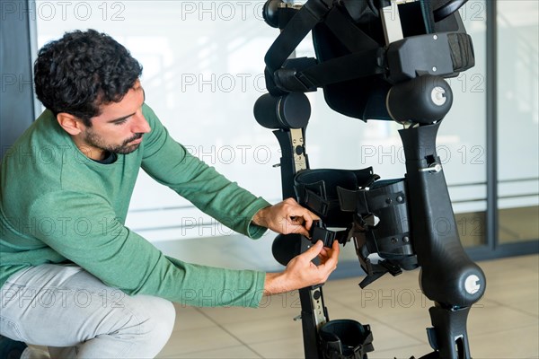 Mechanical exoskeleton engineer checking the mechanisms before the arrival of patients. Physiotherapy in a modern hospital: Robotic skeleton. Physiotherapy Rehabilitation Scientists