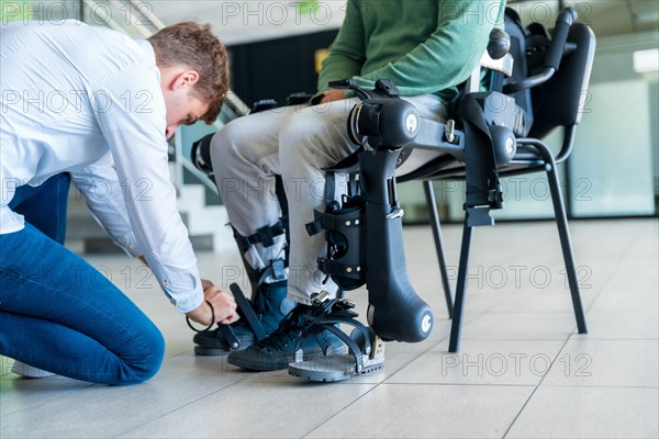 Mechanical exoskeleton. Physiotherapy in a modern hospital: Physiotherapist placing the tapes on the knees of the disabled person to place his robotic skeleton