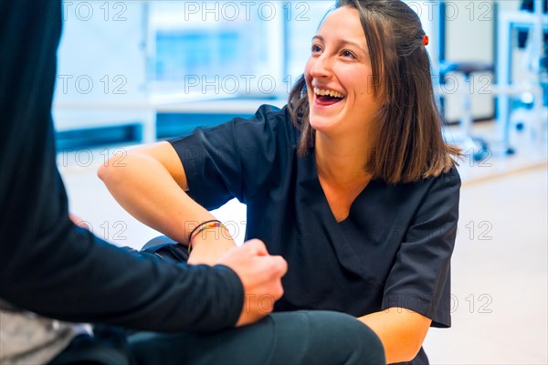 Mechanical exoskeleton. Physiotherapy smiling in modern hospital: Female physiotherapist helping disabled person with robotic skeleton with tapes. Futuristic rehabilitation