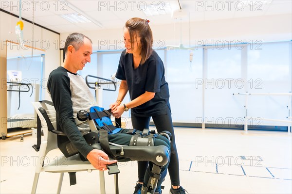 Mechanical exoskeleton. Physiotherapy assistant placing tapes on disabled person with robotic skeleton. Futuristic rehabilitation