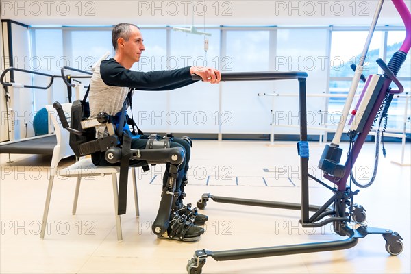 Mechanical exoskeleton. Disabled person with robotic skeleton in rehabilitation trying to get up alone