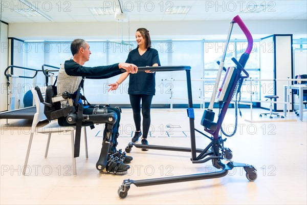 Mechanical exoskeleton. Physiotherapy assistant lifting disabled person with robotic skeleton to get up. Futuristic rehabilitation