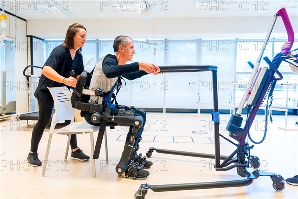 Mechanical exoskeleton. Physiotherapy assistant lifting disabled person with robotic skeleton to get up. Futuristic rehabilitation