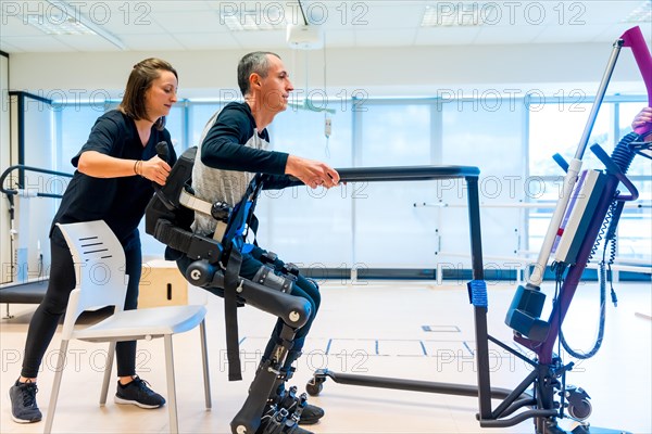 Mechanical exoskeleton. Physiotherapy medical assistant lifting disabled person with robotic skeleton to get up. Futuristic rehabilitation