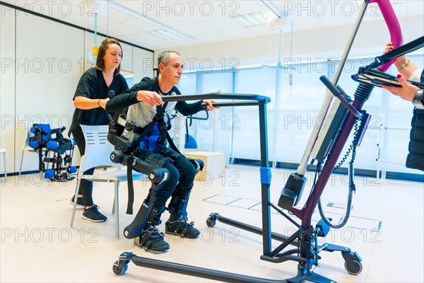 Mechanical exoskeleton. Female physiotherapy medical assistant lifting disabled person with robotic skeleton. Futuristic rehabilitation