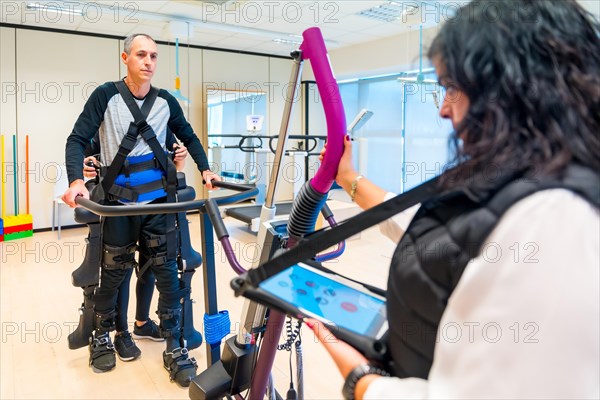 Mechanical exoskeleton. Female physiotherapy medical assistant with disabled person lifted with robotic skeleton. Futuristic rehabilitation