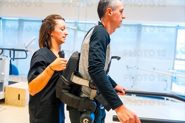 Mechanical exoskeleton. Female physiotherapy medical assistant helping disabled person with robotic skeleton to walk. Futuristic rehabilitation