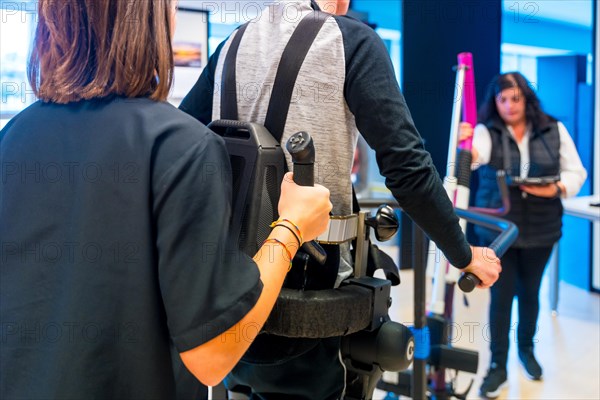 Mechanical exoskeleton. Female physiotherapy medical assistant helping disabled person with robotic skeleton to walk. Futuristic rehabilitation