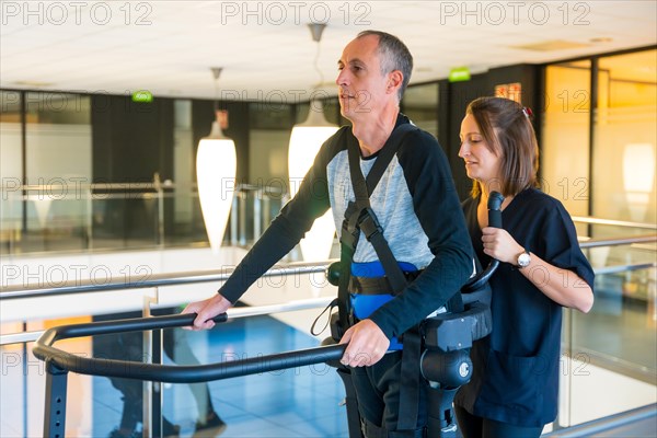 Mechanical exoskeleton. Female physiotherapy doctor helping disabled person with robotic skeleton to walk. Futuristic rehabilitation