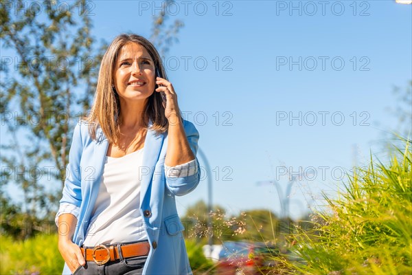Proud casual businesswoman talking to the phone standing on a residential urban district