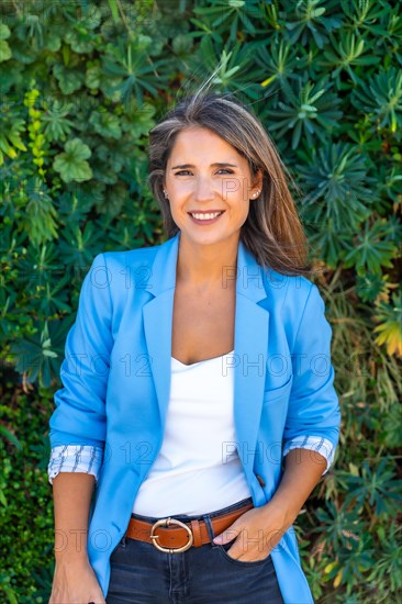 Portrait of a casual businesswoman smiling outdoors next to a green area