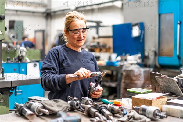 Female factory worker operator working in numerical control sector measuring drill bits