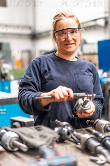 Female factory worker operator working in numerical control sector measuring drill bits