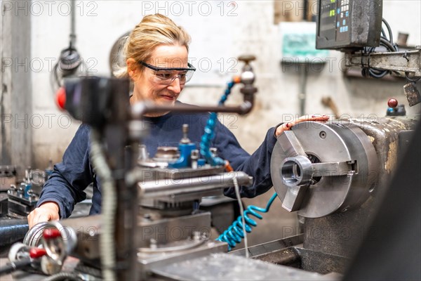 Female factory worker operator working in the control sector on a metal milling machine
