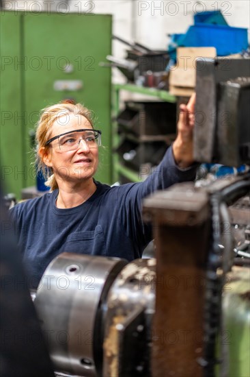 Female factory worker operator working in the control sector on a metal milling machine