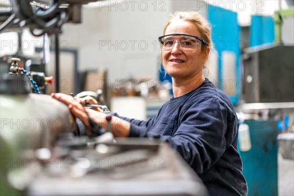 Portrait of female factory worker operator working in the control sector on a metal milling machine