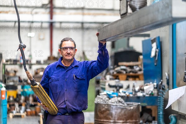 Factory worker operator in the numerical control sector delivering a raised metal part on a machine to a client