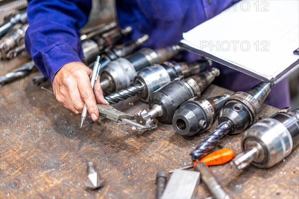 Factory worker operator of the numerical control sector measuring the drill bits