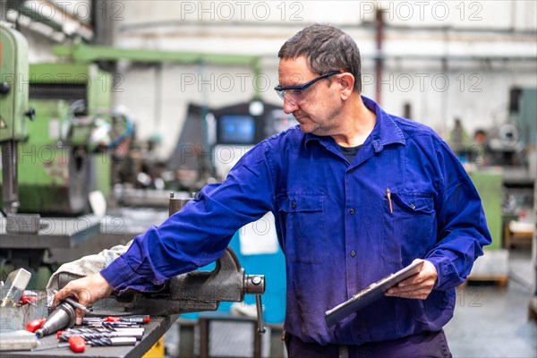 Factory worker operator in the numerical control sector making a report to send to suppliers