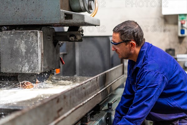 Factory worker operator in the numerical control sector preparing a machine