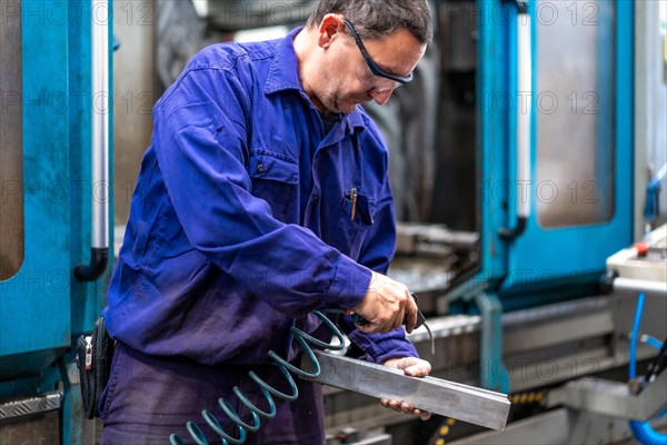 Factory worker operator in the numerical control sector cleaning a part with compressed air