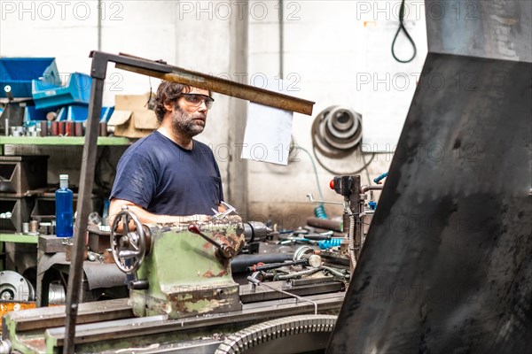 Factory worker operator in the numerical control sector working on a machine