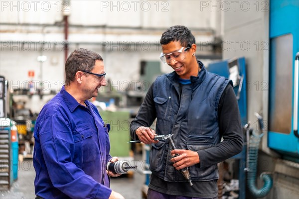 Instructor teaching and speaking the trade to a metal industrial factory worker in the numerical control sector