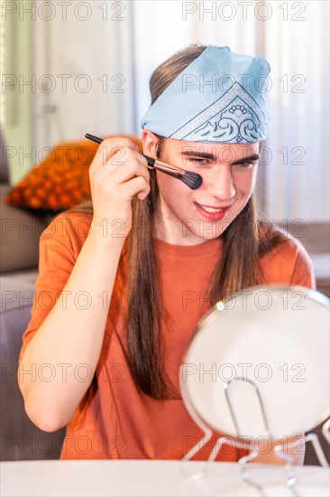 Vertical photo of a gay man applying make up at home