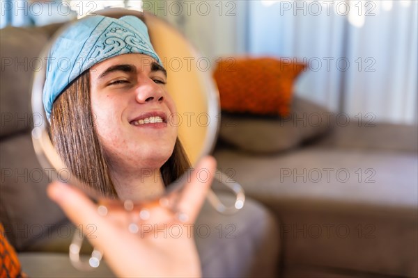 Satisfied gay man gazing his self in the mirror using a hand mirror at home