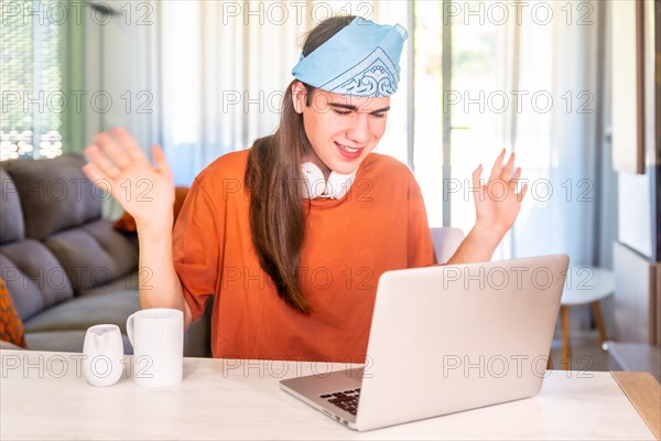 Surprised and happy transgender person using laptop working on remote at home