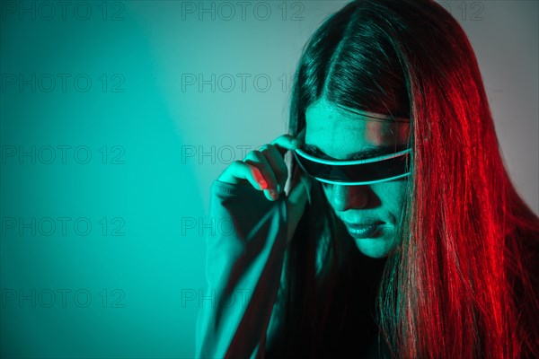 Futuristic studio portrait with neon lights of a gay man with long hair using smart goggles