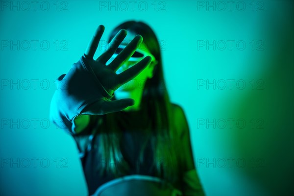 Futuristic studio portrait with neon lights of a transgender man experimenting while using smart goggles