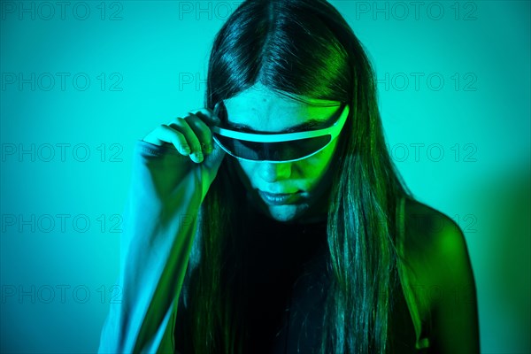 Futuristic studio portrait with neon lights of a non binary person with long hair using smart goggles