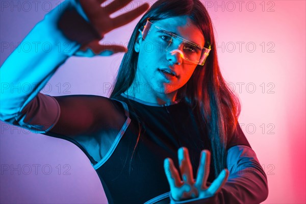 Futuristic studio portrait with neon lights of a transgender person experimenting in the metaverse using augmented reality goggles