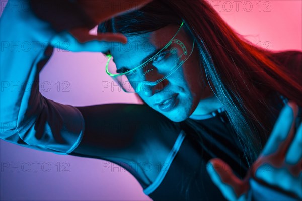 Futuristic studio portrait with neon lights of an androgynous person experimenting in the metaverse using augmented reality goggles