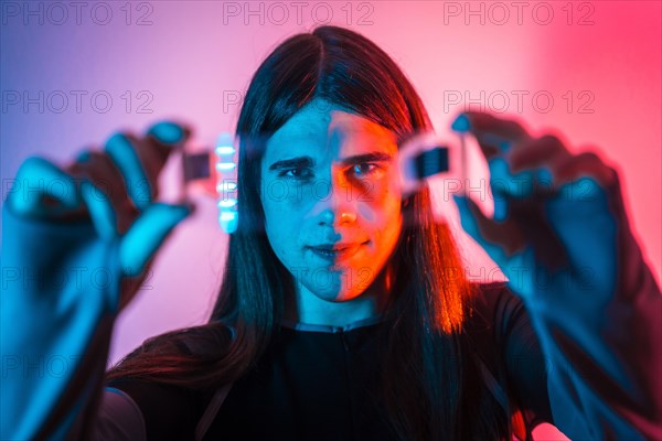 Futuristic studio portrait with neon lights of a transgender person showing Augmented reality goggles