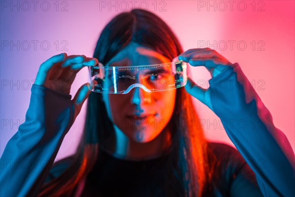 Futuristic studio portrait with neon lights of a transgender person putting on augmented reality goggles